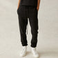Person wearing black jogger pants and white sneakers on a light gray background